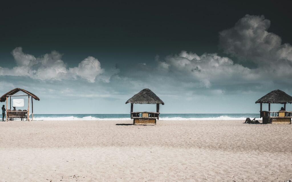 La Union Beachfront – Peaceful Ocean View for Campers Beachfront huts in La Union, Philippines with soft sand and cloudy skies — a peaceful coastal camping destination